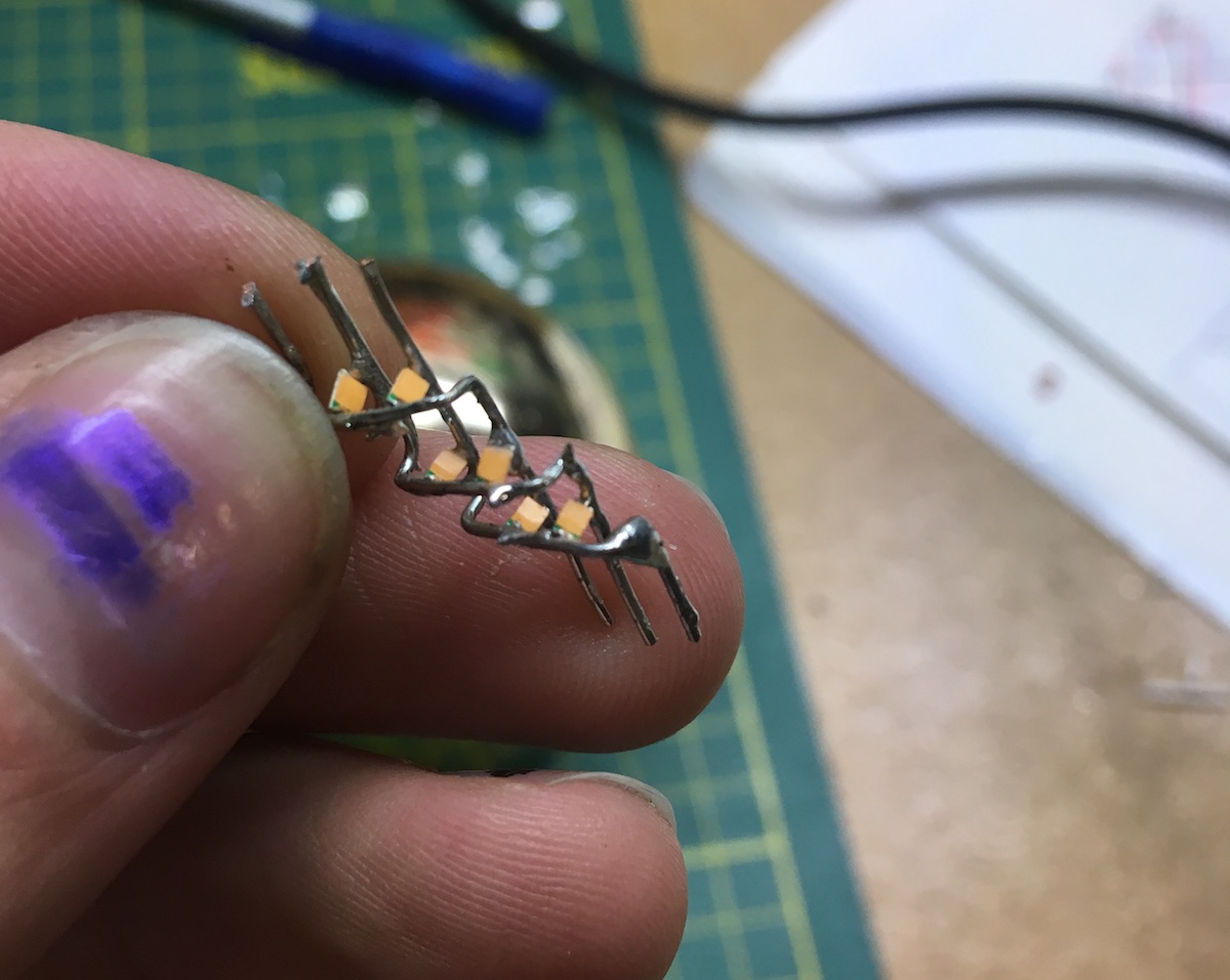 tiny LED sculpture with six surface-mount LEDs soldered directly onto three wires, flashing in an ascending pattern