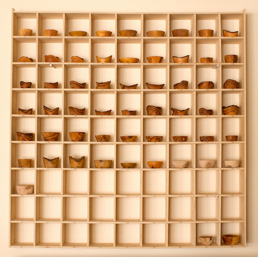 A hand-made 9x9 open-faced shelf mostly filled with hand-turned wooden bowls